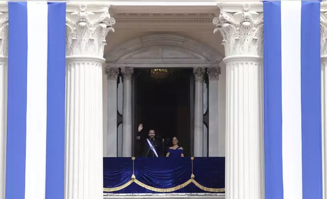 El Salvador's President Nayib Bukele waves from a balcony accompanied by first lady Gabriela Roberta Rodríguez after he was sworn in for a second term, in San Salvador, El Salvador, Saturday, June 1, 2024. (AP Photo/Salvador Melendez)