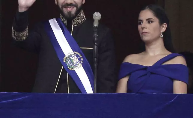 El Salvador's President Nayib Bukele waves from a balcony accompanied by first lady Gabriela Roberta Rodríguez after he was sworn in for a second term, in San Salvador, El Salvador, Saturday, June 1, 2024. (AP Photo/Salvador Melendez)