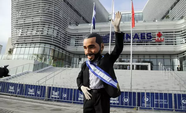 A supporter of El Salvador's President Nayib Bukele, wearing a mask depicting him, poses for a photo outside the National Library prior to his inauguration for a second term in San Salvador, El Salvador, Saturday, June 1, 2024. (AP Photo/Salvador Melendez)