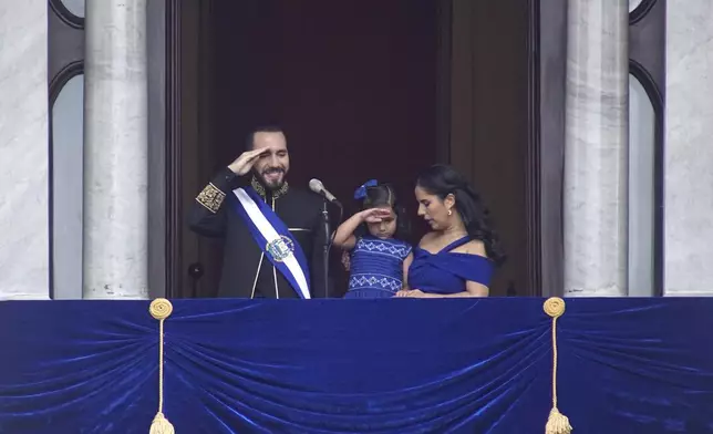 El Salvador's President Nayib Bukele and his daughter Layla salute while standing on a balcony with first lady Gabriela Roberta Rodríguez, after he was sworn in for a second term, in San Salvador, El Salvador, Saturday, June 1, 2024. (AP Photo/Salvador Melendez)
