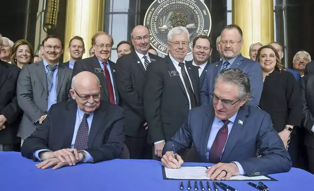FILE - State legislators and officials watch April 26, 2019 as Gov. Doug Burgum signs Senate Bill 2001, which authorizes a $50 million endowment for the proposed Theodore Roosevelt Presidential Library and Museum in Medora. Seated at left is Secretary of State Al Jaeger who certified the bill. (Tom Stromme/The Bismarck Tribune via AP, File)