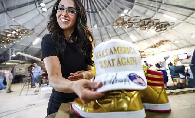 Rep. Lauren Boebert, R-Colo., arranges a Make America Great Again hat and a pair of gold Converse All-Stars basketball shoes on the stage at her primary election watch party Tuesday, June 25, 2024, in Windsor, Colo. (Hart Van Denburg/Colorado Public Radio via AP)