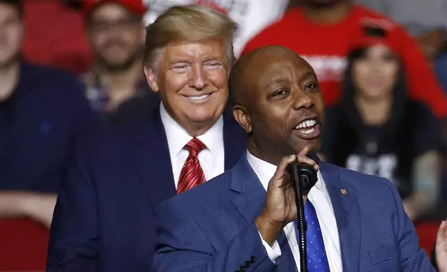 FILE - Sen. Tim Scott, R-S.C., speaks in front of President Donald Trump during a campaign rally, Feb. 28, 2020, in North Charleston, S.C. Scott's life has been a series of people offering a hand that helped him get ahead. Now the senator from South Carolina waits to see if former President Donald Trump gives him another boost and makes him the vice presidential nominee. (AP Photo/Patrick Semansky, File)