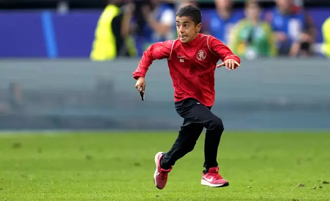 A young pitch invader runs during a Group F match between Turkey and Portugal at the Euro 2024 soccer tournament in Dortmund, Germany, Saturday, June 22, 2024. (AP Photo/Darko Vojinovic)