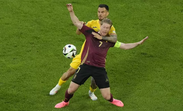 Belgium's Kevin De Bruyne , front, vies for the ball with Romania's Marius Marin during a Group E match between Belgium and Romania at the Euro 2024 soccer tournament in Cologne, Germany, Saturday, June 22, 2024. (AP Photo/Frank Augstein)
