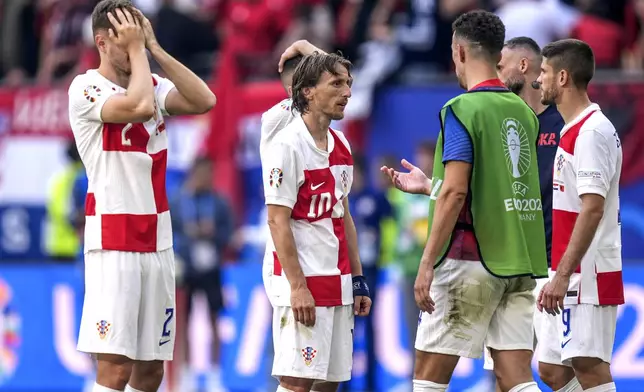 Croatia's Luka Modric, center, and his teammate stand on the pitch after a Group B match between Croatia and Albania at the Euro 2024 soccer tournament in Hamburg, Germany, Wednesday, June 19, 2024. (Marcus Brandt/dpa via AP)