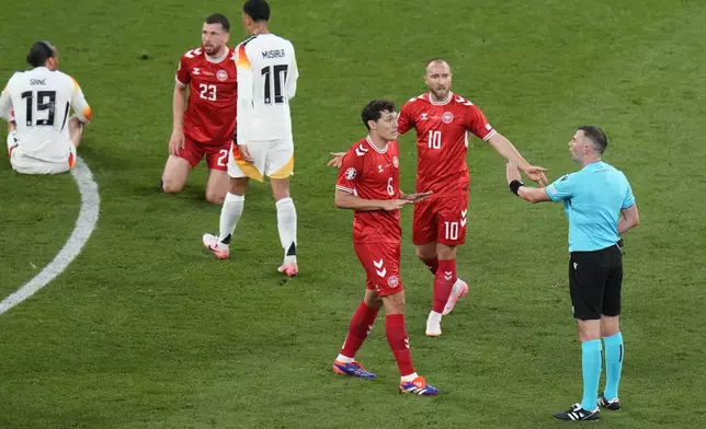 Denmark's Andreas Christensen, centre, argues with referee Michael Oliver during a round of sixteen match between Germany and Denmark at the Euro 2024 soccer tournament in Dortmund, Germany, Saturday, June 29, 2024. (AP Photo/Hassan Ammar)