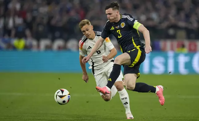 Scotland's Andrew Robertson, front, duels for the ball with Germany's Joshua Kimmich during a Group A match between Germany and Scotland at the Euro 2024 soccer tournament in Munich, Germany, Friday, June 14, 2024. (AP Photo/Antonio Calanni)