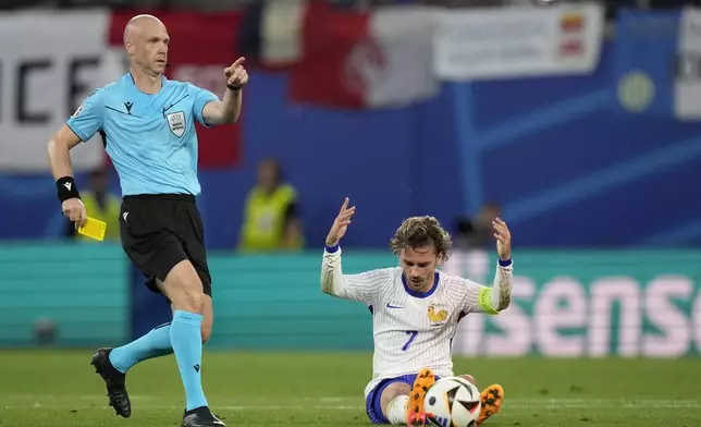 Referee Anthony Taylor of England, left, pulls out a yellow card, after a foul play against Antoine Griezmann of France, right, by Jerdy Schouten of the Netherlands during a Group D match between the Netherlands and France at the Euro 2024 soccer tournament in Leipzig, Germany, Friday, June 21, 2024. (AP Photo/Mathias Schrader)