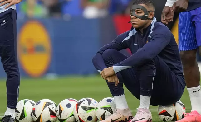 France's Kylian Mbappe with face mask during the warm up before a Group D match between the Netherlands and France at the Euro 2024 soccer tournament in Leipzig, Germany, Friday, June 21, 2024. (AP Photo/Ariel Schalit)