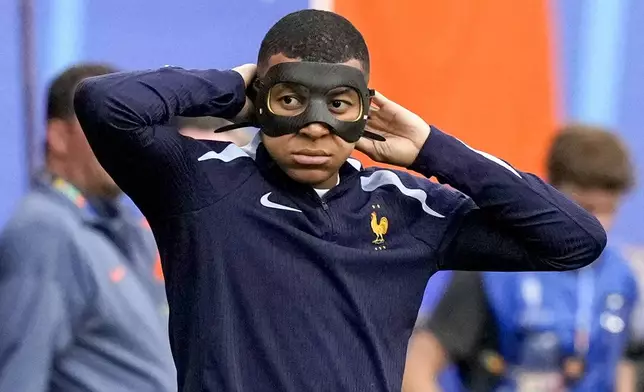 France's Kylian Mbappe warms up with a face mask prior a Group D match between the Netherlands and France at the Euro 2024 soccer tournament in Leipzig, Germany, Friday, June 21, 2024. (AP Photo/Antonio Calanni)