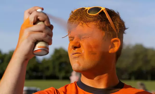 A Dutch supporter spray paints his face orange as he arrives for the Group D match between the Netherlands and France at the Euro 2024 soccer tournament in Leipzig, Germany, Friday, June 21, 2024. (AP Photo/Hassan Ammar)