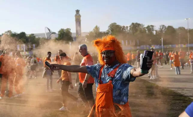 A Dutch fan holds a smoke flare outside the stadium ahead of a Group D match between the Netherlands and France at the Euro 2024 soccer tournament in Leipzig, Germany, Friday, June 21, 2024. (AP Photo/Sergei Grits)