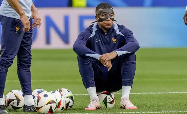 France's Kylian Mbappe attends the warm up with a face mask prior to a Group D match between the Netherlands and France at the Euro 2024 soccer tournament in Leipzig, Germany, Friday, June 21, 2024. (AP Photo/Antonio Calanni)