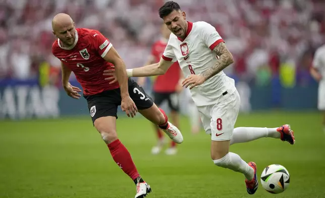 Poland's Jakub Moder, right, and Austria's Gernot Trauner fight for the ball during a Group D match between Poland and Austria at the Euro 2024 soccer tournament in Berlin, Germany, Friday, June 21, 2024. (AP Photo/Ebrahim Noroozi)