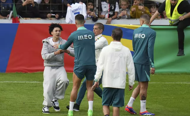 A pitch invader tries to reach Portugal's Cristiano Ronaldo during a training session in Gutersloh, Germany, Friday, June 14, 2024. Portugal will play against Czech Republic during their Group F soccer match at the Euro 2024 soccer tournament on June 18. (AP Photo/Hassan Ammar)
