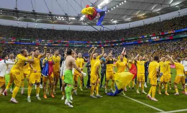 Romania's players celebrate at the end of the match during a Group E match between Slovakia and Romania at the Euro 2024 soccer tournament in Frankfurt, Germany, Wednesday, June 26, 2024. (AP Photo/Frank Augstein)