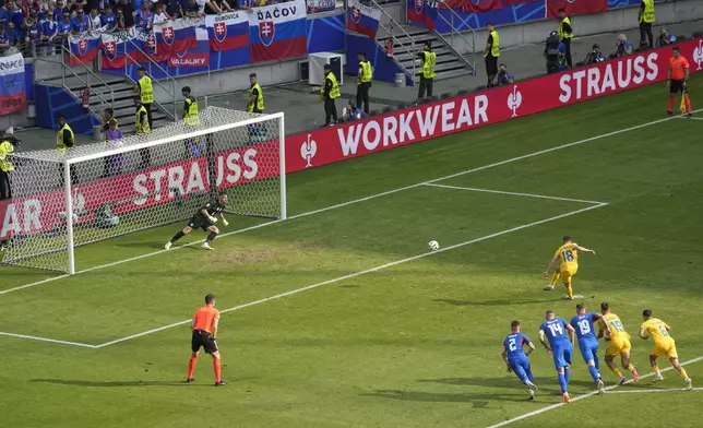 Romania's Razvan Marin (18), scores from the penalty spot, his side's first goal against Slovakia, during a Group E match at the Euro 2024 soccer tournament in Frankfurt, Germany, Wednesday, June 26, 2024. (AP Photo/Darko Vojinovic)