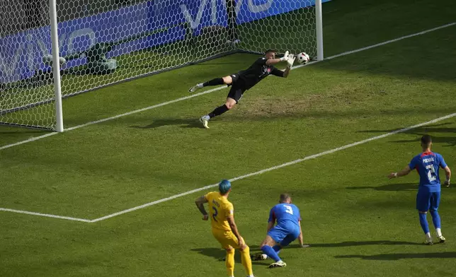 Slovakia's goalkeeper Martin Dubravka, top, saves a shot by Romania's Andrei Ratiu, bottom left, during a Group E match at the Euro 2024 soccer tournament in Frankfurt, Germany, Wednesday, June 26, 2024. (AP Photo/Darko Vojinovic)