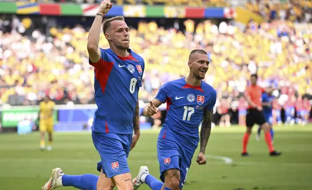 Slovakia's Ondrej Duda, left, celebrates scoring the opening goal against Romania during a Group E match at the Euro 2024 soccer tournament in Frankfurt, Germany, Wednesday, June 26, 2024. (Arne Dedert/dpa via AP)