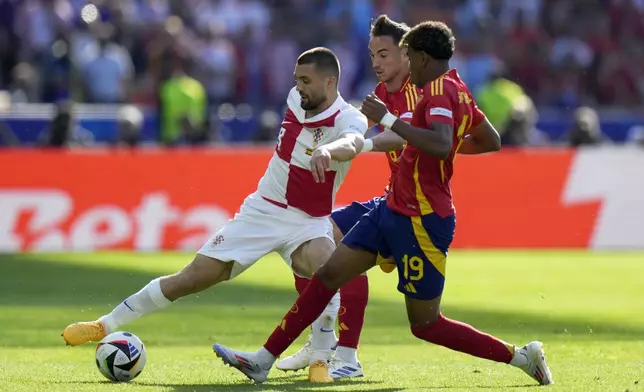 Croatia's Mateo Kovacic, left, vies for the ball with Spain's Fabian Ruiz and Lamine Yamal, right, during a Group B match between Spain and Croatia at the Euro 2024 soccer tournament in Berlin, Germany, Saturday, June 15, 2024. (AP Photo/Sergei Grits)