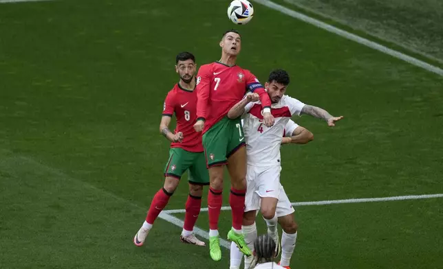 Portugal's Cristiano Ronaldo jumps for the ball with Turkey's Samet Akaydin, right, during a Group F match between Turkey and Portugal at the Euro 2024 soccer tournament in Dortmund, Germany, Saturday, June 22, 2024. (AP Photo/Michael Probst)