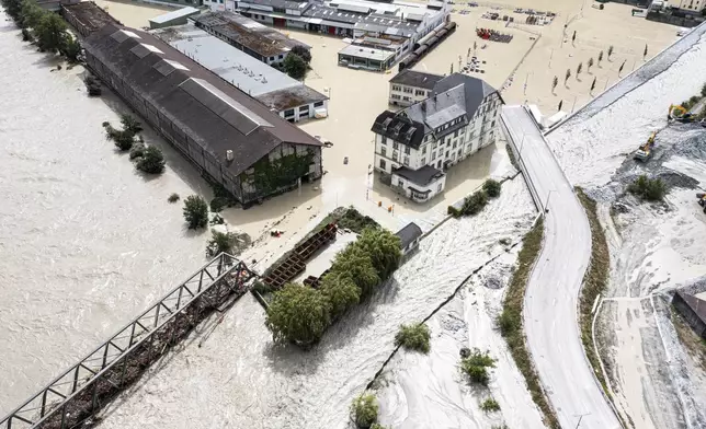 A view of the Rhone river, at left, and the Navizence river overflowing in the industrial zone that produces aluminium "Constellium," following the storms that caused major flooding, in Chippis, Switzerland, Sunday, June 30, 2024. The Rhone river burst its banks in several areas of Valais canton, flooding a highway and a railway line. (Olivier Maire/Keystone via AP)