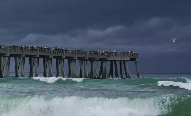 People gather on Navarre Beach Fishing Pier despite storm clouds approach the shore in Navarre Beach, Fla., Sunday, June 16, 2024. (AP Photo/Kiichiro Sato)