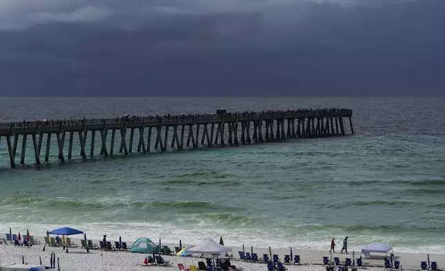 People gather on and around Navarre Beach Fishing Pier despite storm clouds approach the shore in Navarre Beach, Fla., Sunday, June 16, 2024. (AP Photo/Kiichiro Sato)