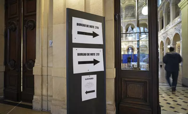 A voter arrives at a polling station to vote in the first round of the French parliamentary election, in Lyon, central France, Sunday, June 30, 2024. Voters across mainland France are casting ballots in the first round of an exceptional parliamentary election. (AP Photo/Laurent Cipriani)