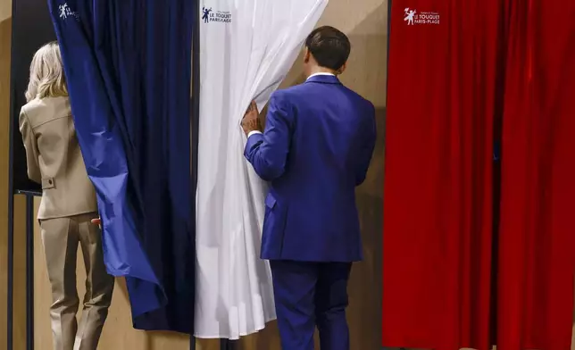 French President Emmanuel Macron and his wife Brigitte Macron enter the voting booth before voting in Le Touquet-Paris-Plage, northern France, Sunday, June 30, 2024. France is holding the first round of an early parliamentary election that could bring the country's first far-right government since Nazi occupation during World War II. The second round is on July 7, and the outcome of the vote remains highly uncertain (Yara Nardi, Pool via AP)