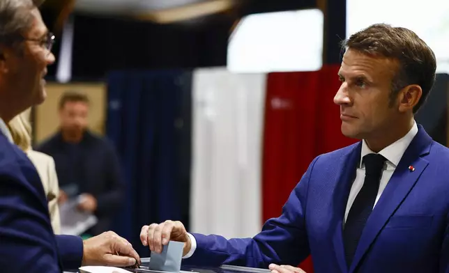 French President Emmanuel Macron, right, casts his ballot to vote in the first round of the early French parliamentary election, in Le Touquet-Paris-Plage, northern France, Sunday, June 30, 2024. France is holding the first round of an early parliamentary election that could bring the country's first far-right government since Nazi occupation during World War II. The second round is on July 7, and the outcome of the vote remains highly uncertain (Yara Nardi, Pool via AP)