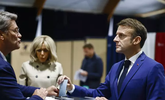 French President Emmanuel Macron, right, casts his ballot to vote in the first round of the early French parliamentary election, in Le Touquet-Paris-Plage, northern France, Sunday, June 30, 2024. France is holding the first round of an early parliamentary election that could bring the country's first far-right government since Nazi occupation during World War II. The second round is on July 7, and the outcome of the vote remains highly uncertain (Yara Nardi, Pool via AP)
