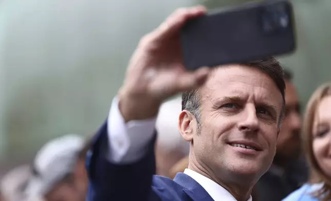 French President Emmanuel Macron takes a selfie with supporters after voting in Le Touquet-Paris-Plage, northern France, Sunday, June 30, 2024. France is holding the first round of an early parliamentary election that could bring the country's first far-right government since Nazi occupation during World War II. The second round is on July 7, and the outcome of the vote remains highly uncertain (Yara Nardi, Pool via AP)