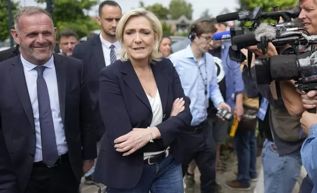 French far right leader Marine Le Pen, center, with local mayor Steeve Briois, left, leave after voting in the first round of the parliamentary election, Sunday, June 30, 2024 in Henin-Beaumont, northern France. France is holding the first round of an early parliamentary election that could bring the country's first far-right government since Nazi occupation during World War II. The second round is on July 7, and the outcome of the vote remains highly uncertain. (AP Photo/Thibault Camus)