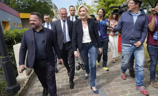 French far right leader Marine Le Pen, center, leaves after voting in the first round of the parliamentary election, Sunday, June 30, 2024 in Henin-Beaumont, northern France. France is holding the first round of an early parliamentary election that could bring the country's first far-right government since Nazi occupation during World War II. The second round is on July 7, and the outcome of the vote remains highly uncertain. (AP Photo/Thibault Camus)