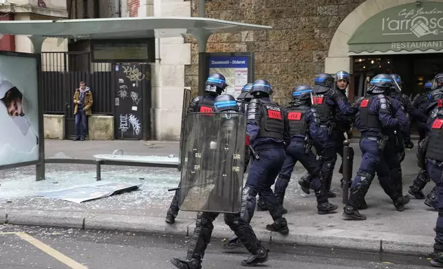 Police stand near a damaged bus shelter during a rally in Paris, Saturday, June 15, 2024. Antiracism groups will join French unions and a brand-new left-wing coalition in protests in Paris and across France on Saturday against the surging nationalist far right as frenzied campaigning is underway ahead of snap parliamentary elections. (AP Photo/Michel Euler)
