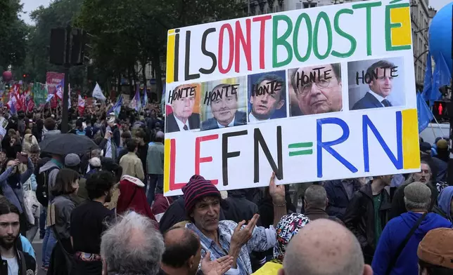 A protester holds an anti-far right banner showing the faces of French Presidents and the word 'Honte' or 'Shame' during a rally in Paris, Saturday, June 15, 2024. Anti-racism groups joined French unions and a brand-new left-wing coalition in protests in Paris and across France on Saturday against the surging nationalist far right as frenzied campaigning is underway ahead of snap parliamentary elections. (AP Photo/Michel Euler)