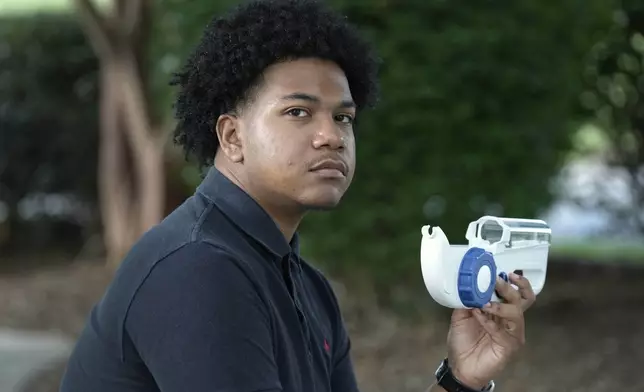 Camden Alderman, 21, who has a rare disease called Wiskott-Aldrich syndrome, holds with an infusion pump he uses near his home in Greensboro, N.C., Wednesday, June 12, 2024. When he was a toddler, doctors removed his spleen because of uncontrolled bleeding. As a young boy, he wound up in the hospital many times and was told he couldn’t play baseball. (AP Photo/Chuck Burton)