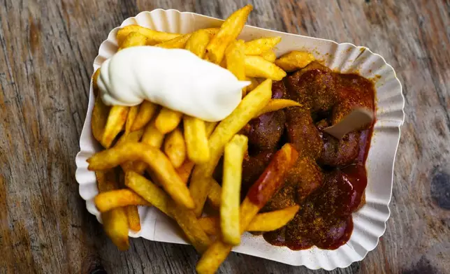 Currywurst, Germany's sausage with curry sauce, served on a cardboard platter with French fries and mayonnaise at Konnopke's Imbiß, a fast-food joint under the tracks at the Eberswalder Straße U-Bahn station, in Berlin, Germany, Friday, May 24, 2024. The currywurst promises to be among the most tantalizing gourmet treats on offer at the European Championship this summer. The currywurst is considered a fast-food delicacy in a country where the humble sausage enjoys great importance. (AP Photo/Markus Schreiber)