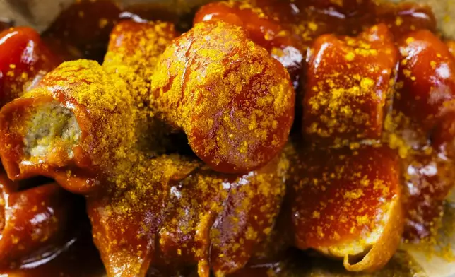Currywurst, Germany's sausage with curry sauce, served on a cardboard at Konnopke's Imbiß, a fast-food joint under the tracks at the Eberswalder Straße U-Bahn station in Berlin, Germany, Thursday, June 6, 2024. The currywurst promises to be among the most tantalizing gourmet treats on offer at the European Championship this summer. The currywurst is considered a fast-food delicacy in a country where the humble sausage enjoys great importance. (AP Photo/Markus Schreiber)