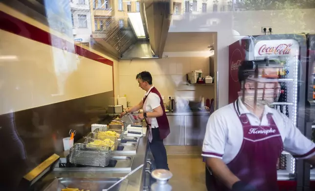 Employees frys and serves Currywurst, Germany's sausage with curry sauce, at Konnopke's Imbiß, a fast-food joint under the tracks at the Eberswalder Straße U-Bahn station in Berlin, Germany, Friday, May 24, 2024. The currywurst promises to be among the most tantalizing gourmet treats on offer at the European Championship this summer. The currywurst is considered a fast-food delicacy in a country where the humble sausage enjoys great importance. (AP Photo/Markus Schreiber)