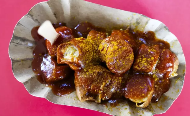 Currywurst, Germany's sausage with curry sauce, served on a cardboard at Konnopke's Imbiß, a fast-food joint under the tracks at the Eberswalder Straße U-Bahn station in Berlin, Germany, Thursday, June 6, 2024. The currywurst promises to be among the most tantalizing gourmet treats on offer at the European Championship this summer. The currywurst is considered a fast-food delicacy in a country where the humble sausage enjoys great importance. (AP Photo/Markus Schreiber)