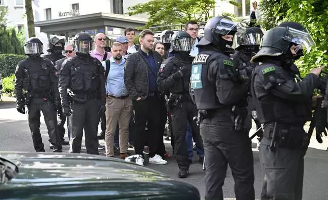 Participants at the AfD party conference are led to the Grugahalle by the police in Essen, Germany, Saturday, June 29, 2024. A few hours before the start of the far right AfD national party conference, demonstrators had their first clash with the police on Saturday morning. (Henning Kaiser/dpa via AP)