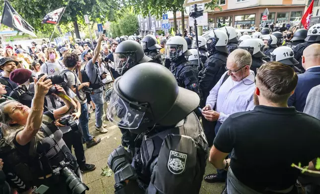 Not far from the Grugahalle, a group of AfD politicians, right, are recognized and surrounded by counter-demonstrators, as the police form a protective ring, in Essen, Germany, Saturday, June 29, 2024. The two-day national party conference of the AfD is taking place in the Grugahalle, including the election of the federal executive committee. Numerous organizations have announced opposition to the meeting and more than a dozen counter-demonstrations. (dpa via AP)