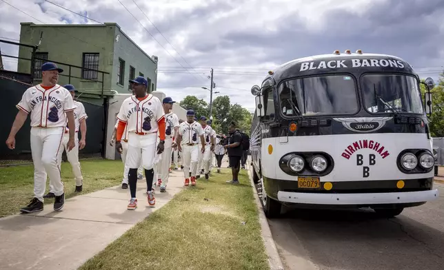 San Francisco Giants players walk past a bus that was used for travel by the Birmingham Black Barons, before the Giants' baseball game against the St. Louis Cardinals at Rickwood Field in Birmingham, Ala., Thursday, June 20, 2024. (Carlos Avila. Gonzalez/San Francisco Chronicle via AP)