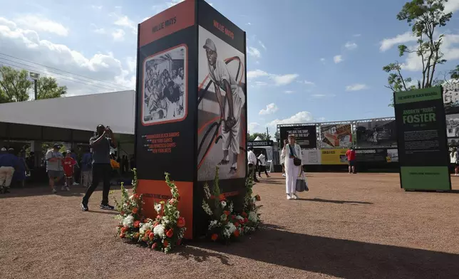 Flowers are seen at the base of a tribute to Willie Mays is seen outside Rickwood Stadium before the start of a baseball game between the St. Louis Cardinals and the San Francisco Giants Thursday, June 20, 2024, in Birmingham, Ala. Mays, who began his professional career with the Birmingham Black Barons of the Negro Leagues in 1948 and played at Rickwood Field, passed away on Tuesday at the age of 93. (AP Photo/Vasha Hunt)