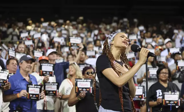 Singer and songwriter Andra Day performs her original song "Rise Up" during a Stand Up To Cancer placard moment during a baseball game between the St. Louis Cardinals and the San Francisco Giants at Rickwood Field, Thursday, June 20, 2024, in Birmingham, Ala. (AP Photo/Vasha Hunt)