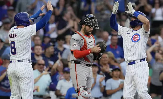 Chicago Cubs' Dansby Swanson, right, celebrates with Ian Happ, left, after hitting a two-run home run, while San Francisco Giants catcher Curt Casali, center, looks at his glove during the second inning of a baseball game in Chicago, Tuesday, June 18, 2024. (AP Photo/Nam Y. Huh)