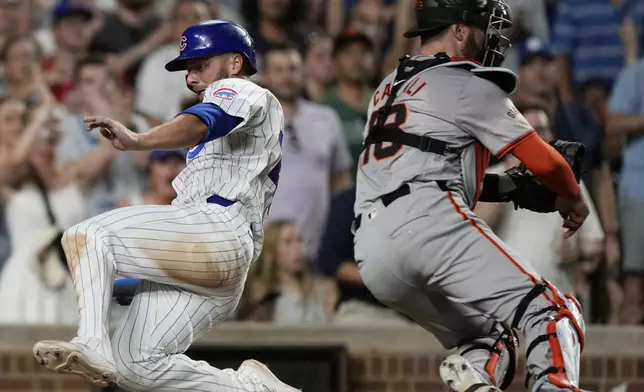 Chicago Cubs' Michael Busch, left, scores as San Francisco Giants catcher Curt Casali waits for the ball during the eighth inning of a baseball game in Chicago, Tuesday, June 18, 2024. (AP Photo/Nam Y. Huh)